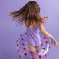 Bambina che balla con ciambella Sweet Hearts su sfondo lilla