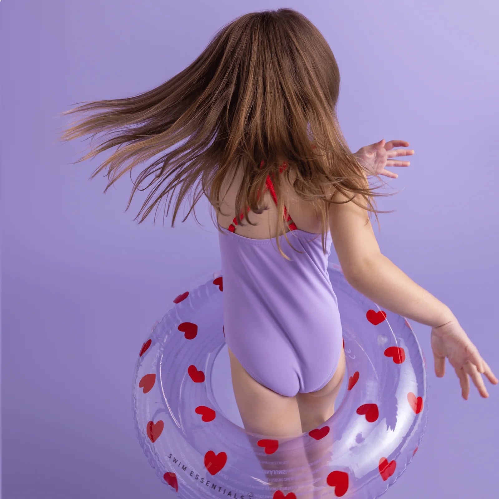 Bambina che balla con ciambella Sweet Hearts su sfondo lilla