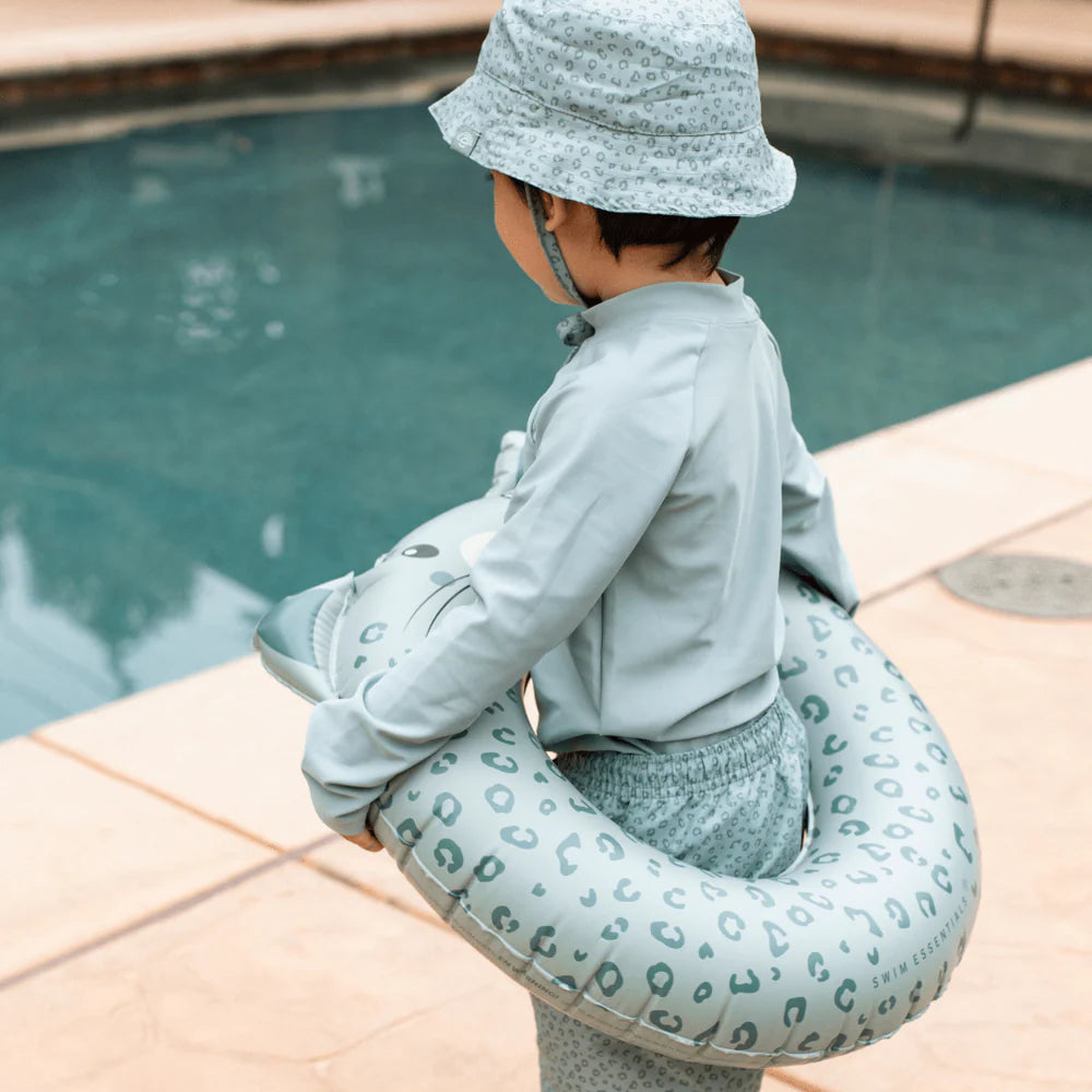 Bambino con ciambella Green Leopard in braccio vicino alla piscina