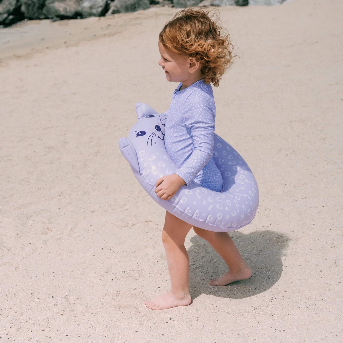 Bambina con ciambella Lila Leopard indossata in spiaggia – vista laterale