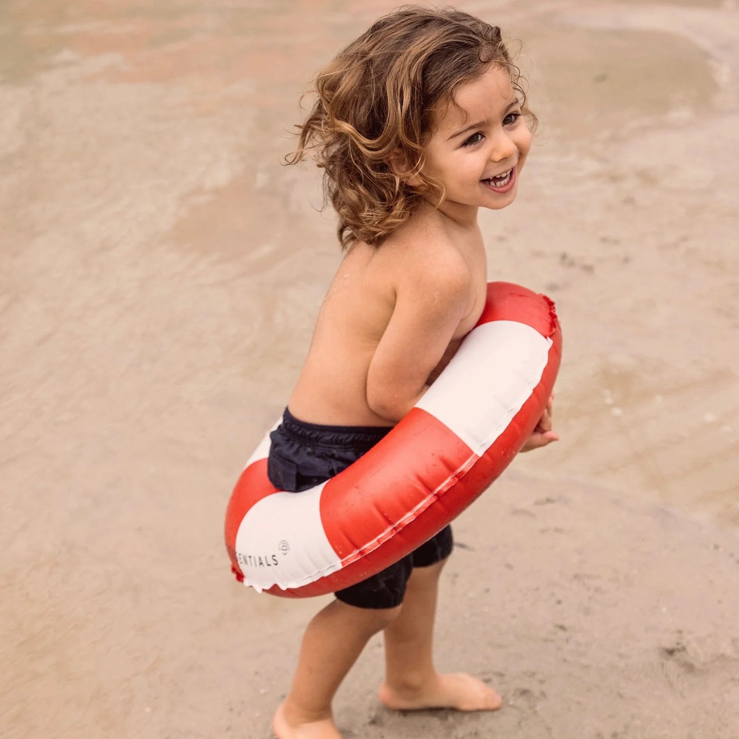 Bambino sorridente con ciambella Life Buoy in spiaggia