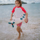 Bambino in spiaggia con ciambella Peter Plane Swim Essentials tra le onde